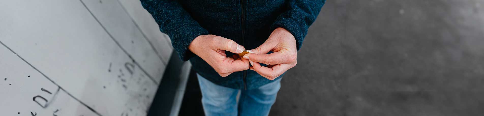 Zwei Hände die den Rand einer Münze ertasten