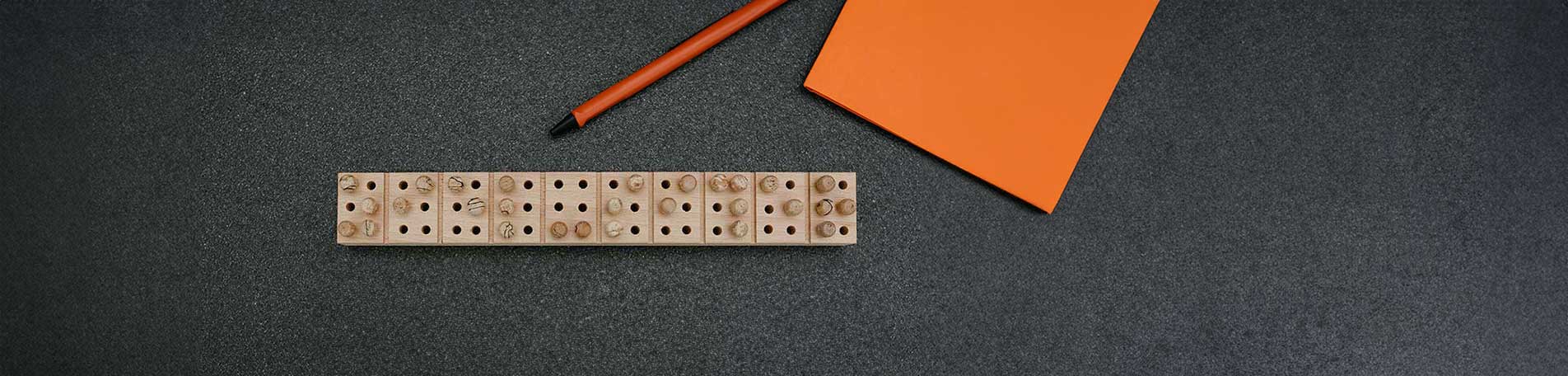 Eine Braille-Steckleiste aus Holz auf der ziel-sicher steht