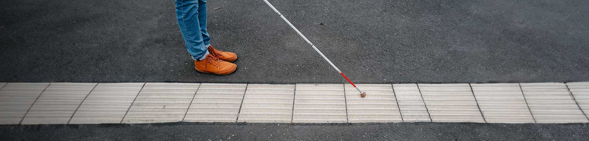 Ein Langstock auf einem Leitstreifen