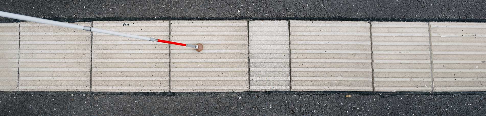 Ein Langstock auf einem Leitstreifen