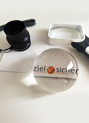 Eine Auswahl von optischen Hilfsmitteln, die das Logo von ziel-sicher vergrößern